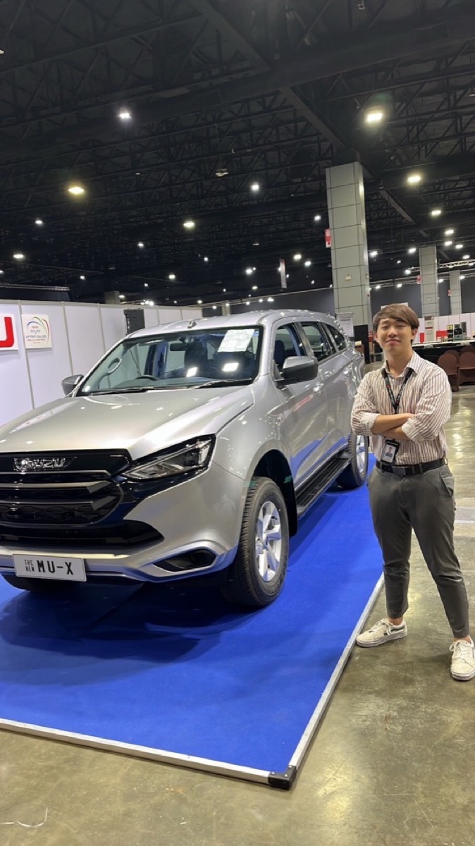 ปันสมัยเป็น Sale Engineer ยืนคู่รถ Isuzu MU-X ในงานแสดงรถ